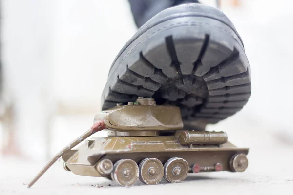 一只军队的靴子踩在一个破损的玩具罐上 乌克兰战争 对平民的破坏 — 图库照片