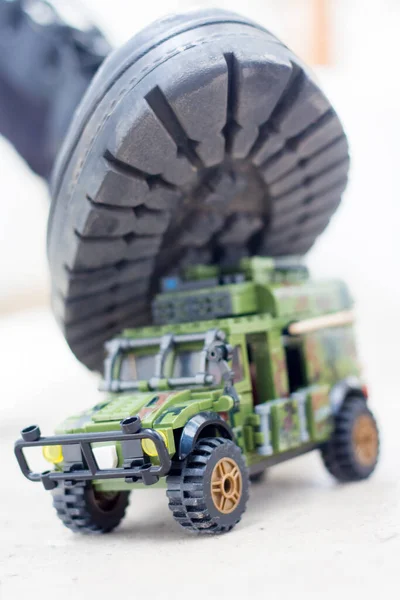 Army boot steps on a child's toy. War in Ukraine, destruction of the civilian population