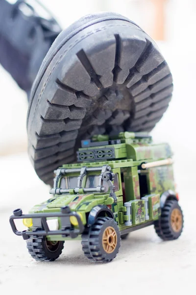 Army boot steps on a child\'s toy. War in Ukraine, destruction of the civilian population