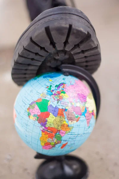 An army boot steps on a globe. War in Ukraine, destruction of the civilian population