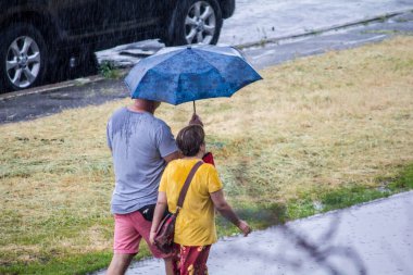 Şemsiyeli kadın baharda yağmurda yürüyor.