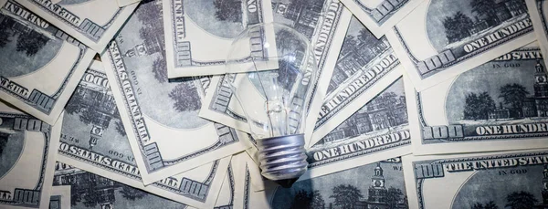 Light bulb on banknotes. Increasing the cost of electricity