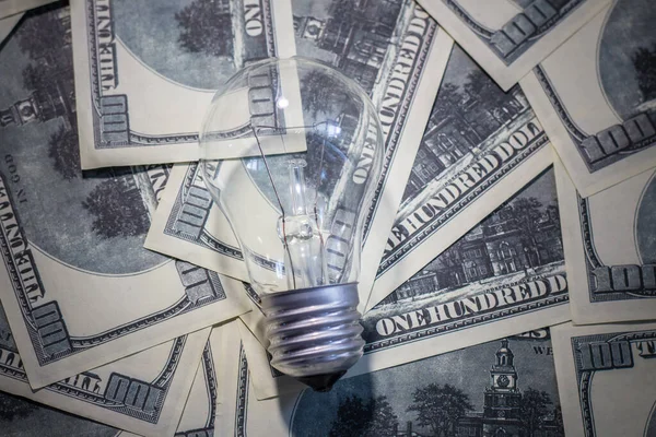 Light bulb on banknotes. Increasing the cost of electricity