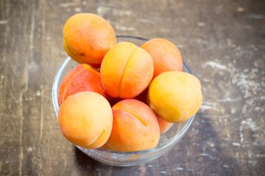 Tahta bir masadaki kasede taze kayısılar.