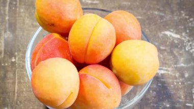 Tahta bir masadaki kasede taze kayısılar.