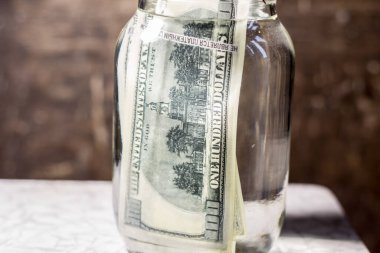 Money banknotes in a glass jar with water