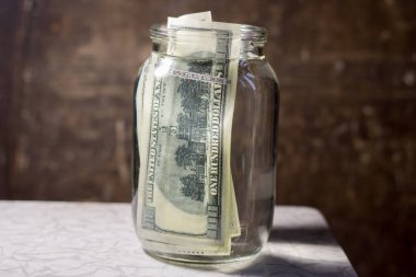 Money banknotes in a glass jar with water