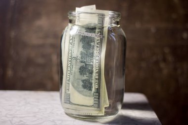 Money banknotes in a glass jar with water