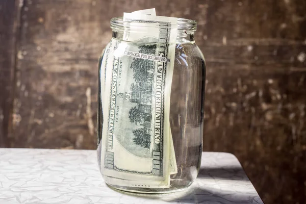 Money banknotes in a glass jar with water