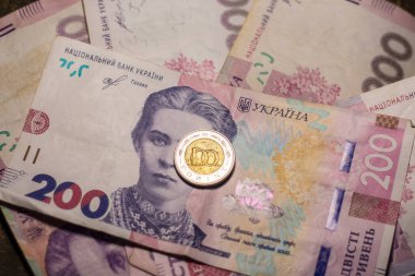 100 forint coin among 200 hryvnia banknotes. Inflation in Ukraine due to the war
