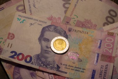 Italy 500 lire coin coins among 200 hryvnia banknotes. Inflation in Ukraine due to the war