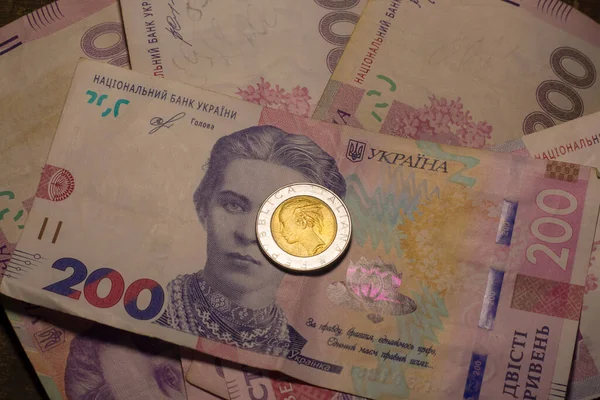 Italy 500 lire coin coins among 200 hryvnia banknotes. Inflation in Ukraine due to the war