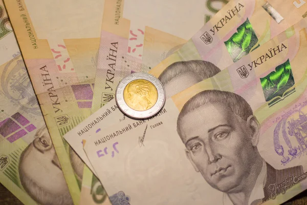 Italy 500 lire coin coins among 200 hryvnia banknotes. Inflation in Ukraine due to the war