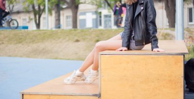 Kız parkta dinleniyor, ağaçların arasında.