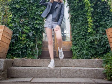 Kız parkta yürüyor, ağaçların arasında.