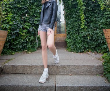 Kız parkta yürüyor, ağaçların arasında.