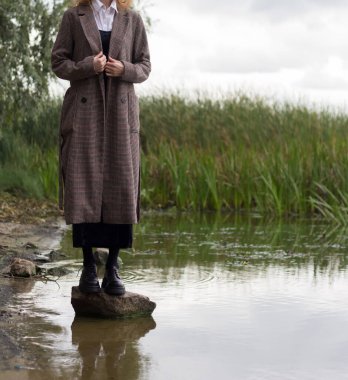 Sonbaharda paltolu bir kız nehrin kenarında duruyor.