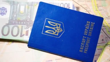 Ukrainian passport with banknotes lies on the map. Departure of refugees due to the war in Ukraine
