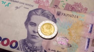 Italy 500 lire coin coins among 200 hryvnia banknotes. Inflation in Ukraine due to the war