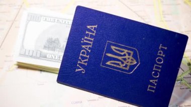 Ukrainian passport with banknotes lies on the map. Departure of refugees due to the war in Ukraine