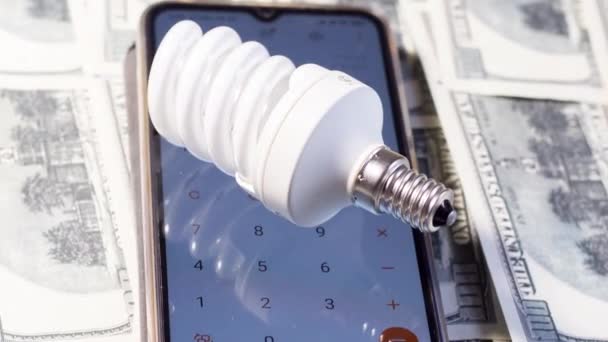 Uma Lâmpada Fluorescente Repousa Sobre Uma Calculadora Notas Economia Eletricidade — Vídeo de Stock