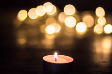 Parlayan lambaların arka planına karşı mum. Ukrayna 'da savaş nedeniyle elektrik kesintisi