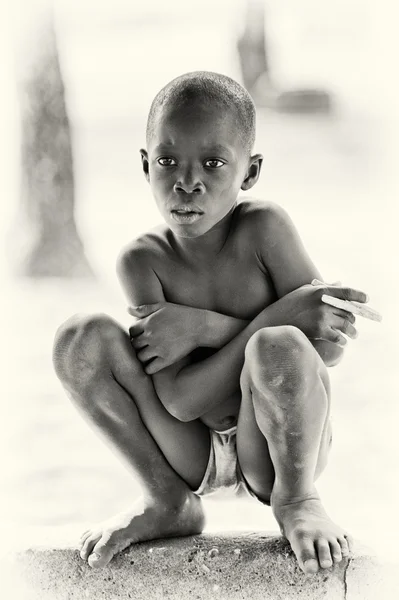 Rapaz ganês senta-se no chão — Fotografia de Stock