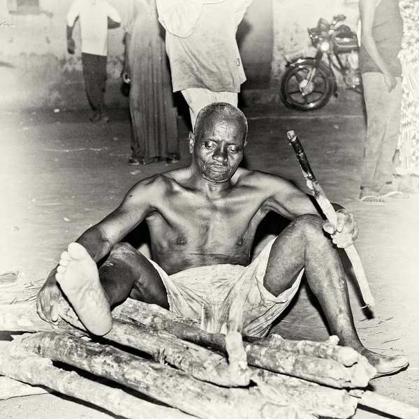 En man från togo sitter på massa trä — Stockfoto