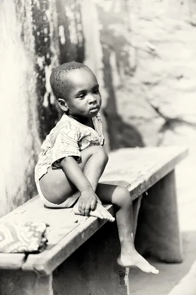 Kleiner Junge aus togo sitzt auf einer bank — Stockfoto