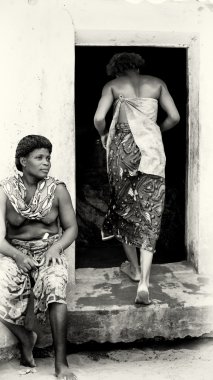 yarı çıplak bir kadın oturur ve diğer kadından togo yaprakları