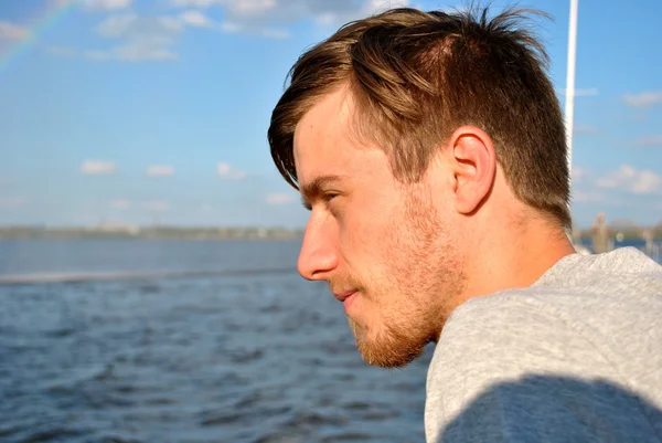 Young man thinks of something in front of the water — Stock Photo, Image