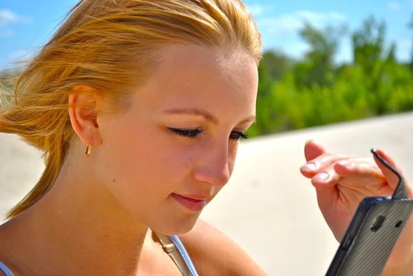 Beautiful girl watches her mobile phone — Stock Photo, Image