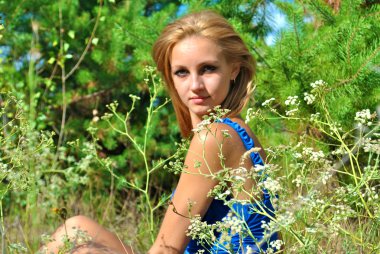 sarışın cinsel kadın model mavi bir elbise içinde muhteşem arasında çim pozlar