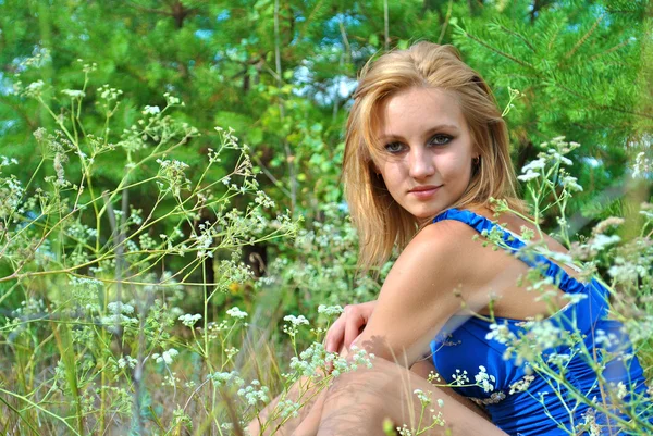 青いドレスで美しい金髪性的女性モデル、草の中で座ってください。 — ストック写真