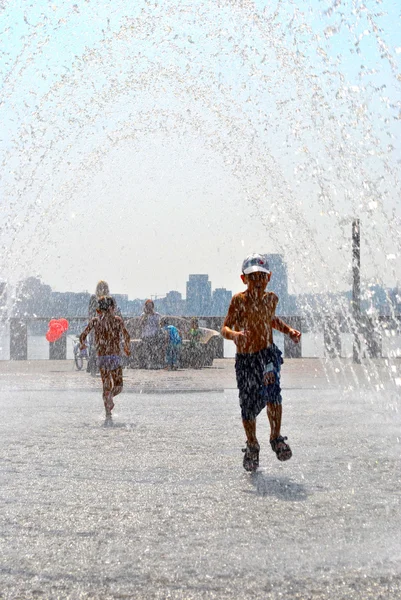 Enfant joue dans une fontaine de rue pendant les vacances — Photo