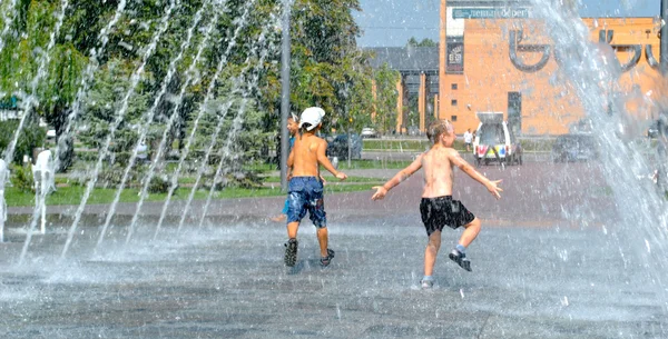 Criança brinca em uma fonte de rua durante o feriado — Fotografia de Stock
