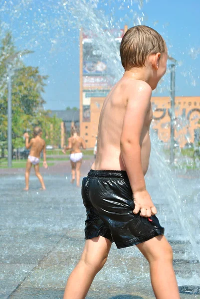 Bambino gioca in una fontana di strada durante la vacanza — Foto Stock