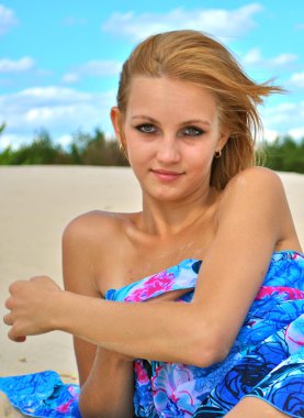 güzel seksi sarışın kız gülümsüyor ve sadece mavi doku kum üzerinde bırakır