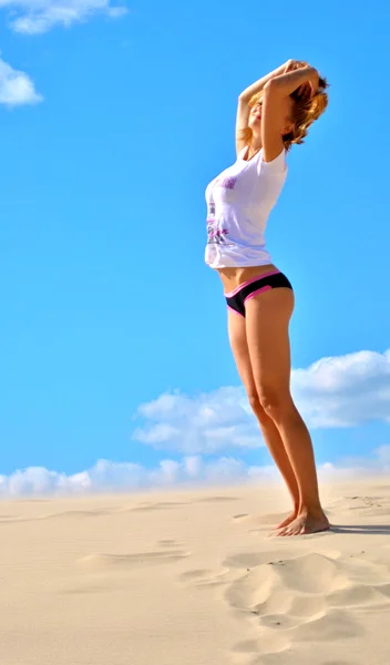 Beautiful sexual blond girl stays on the sand in panties and t-shirt — Stock Photo, Image