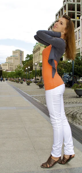 Nice red hair girl poses in orange shirt on the city back ground — Stock Photo, Image