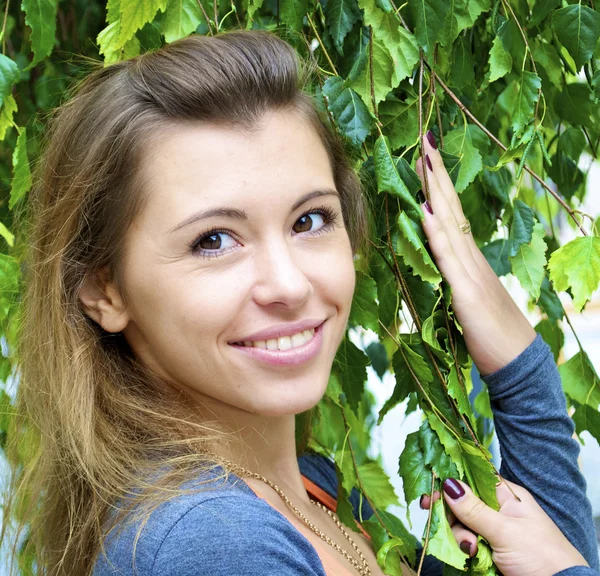 Bella ragazza dai capelli rossi tiene un ramo con foglie — Foto Stock