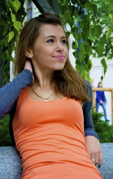 Chica pelirroja se sienta delante en el árbol verde —  Fotos de Stock