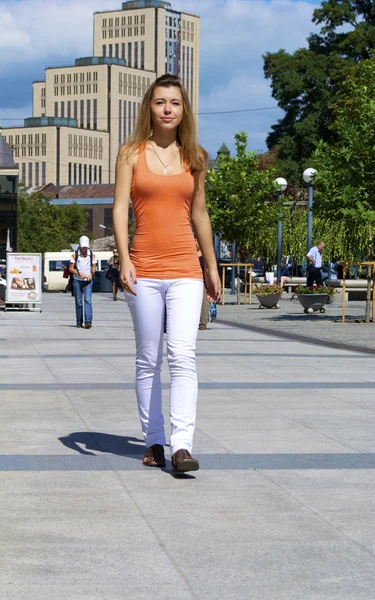Gyönyörű vörös hajú lány egy narancssárga póló séták a városban — Stock Fotó