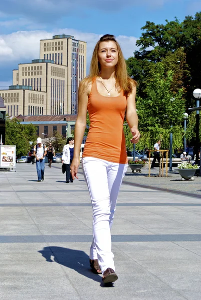 Gyönyörű vörös hajú lány egy narancssárga póló séták a városban — Stock Fotó