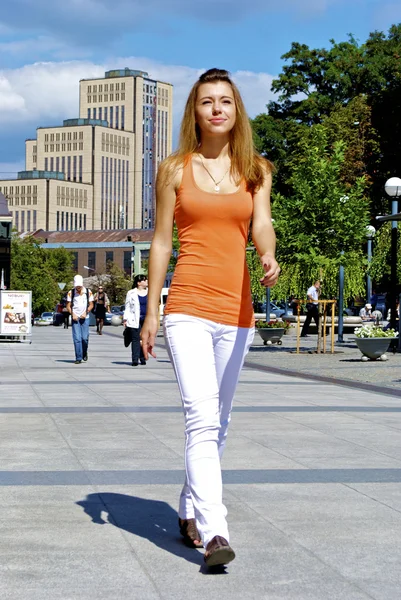 Hermosa chica pelirroja en una camisa naranja camina por la ciudad —  Fotos de Stock