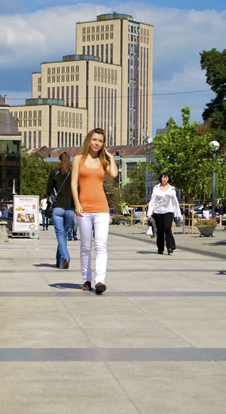 Schöne rothaarige Mädchen in einem orangefarbenen Hemd geht in der Stadt — Stockfoto