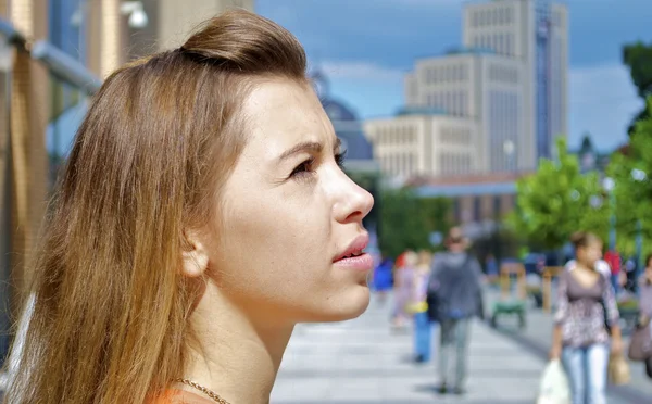 Schöne rothaarige kaukasische Mädchen in einem orangefarbenen Hemd in der Stadt an einem glänzenden Tag — Stockfoto