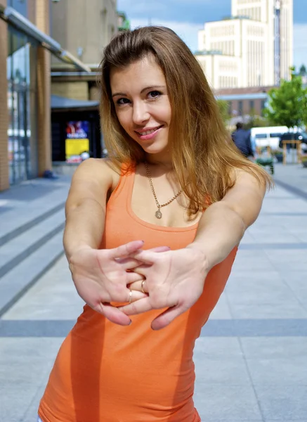 Krásná rusovlasá mladá model v oranžové tričko představuje ve městě zářivý den — Stock fotografie