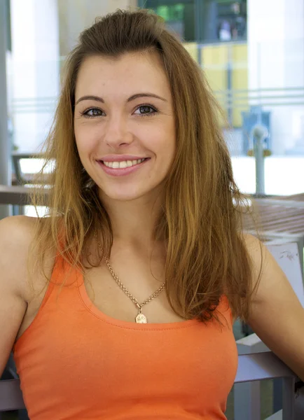 Mooie roodharige meisje in een oranje shirt glimlacht — Stockfoto