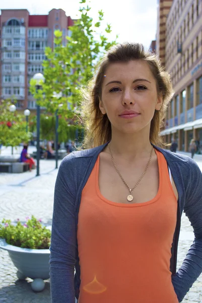 Chica joven pelirroja con una camisa naranja y la ciudad —  Fotos de Stock